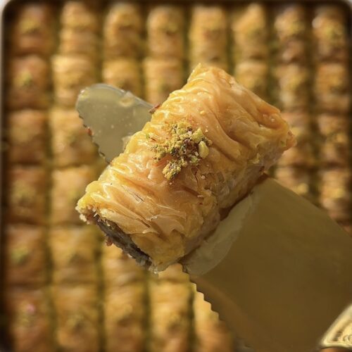 Golden crispy homemade baklava rolls drizzled with syrup and topped with crushed pistachios