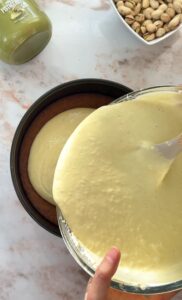 pouring the cheesecake batter on top of the crust