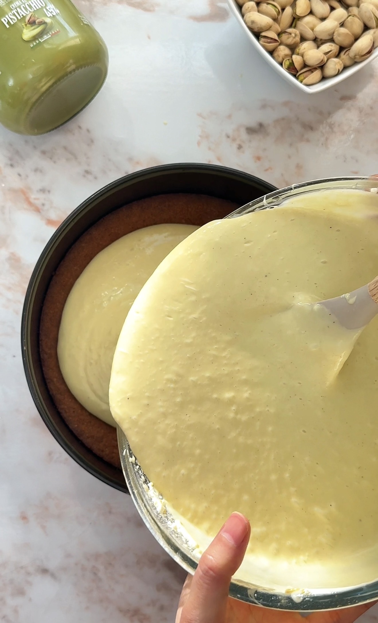 pouring the cheesecake batter on top of the crust