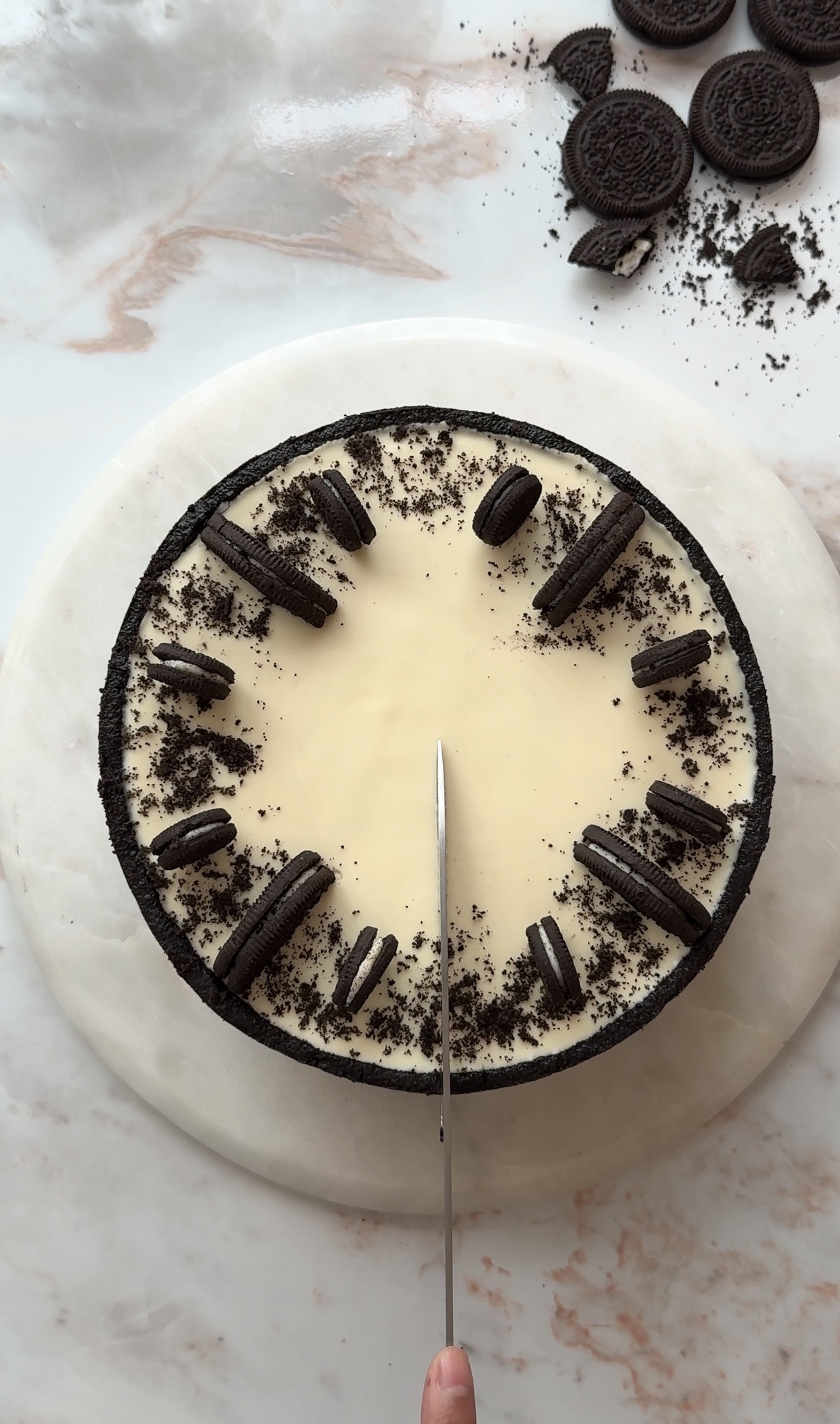 Creamy no bake Oreo cheesecake topped with melted white chocolate and crushed Oreo cookies