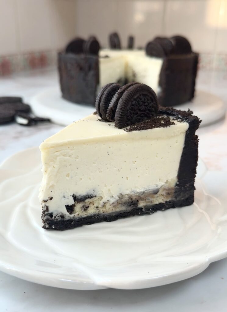 Creamy no bake Oreo cheesecake slice topped with melted white chocolate and crushed Oreo cookies