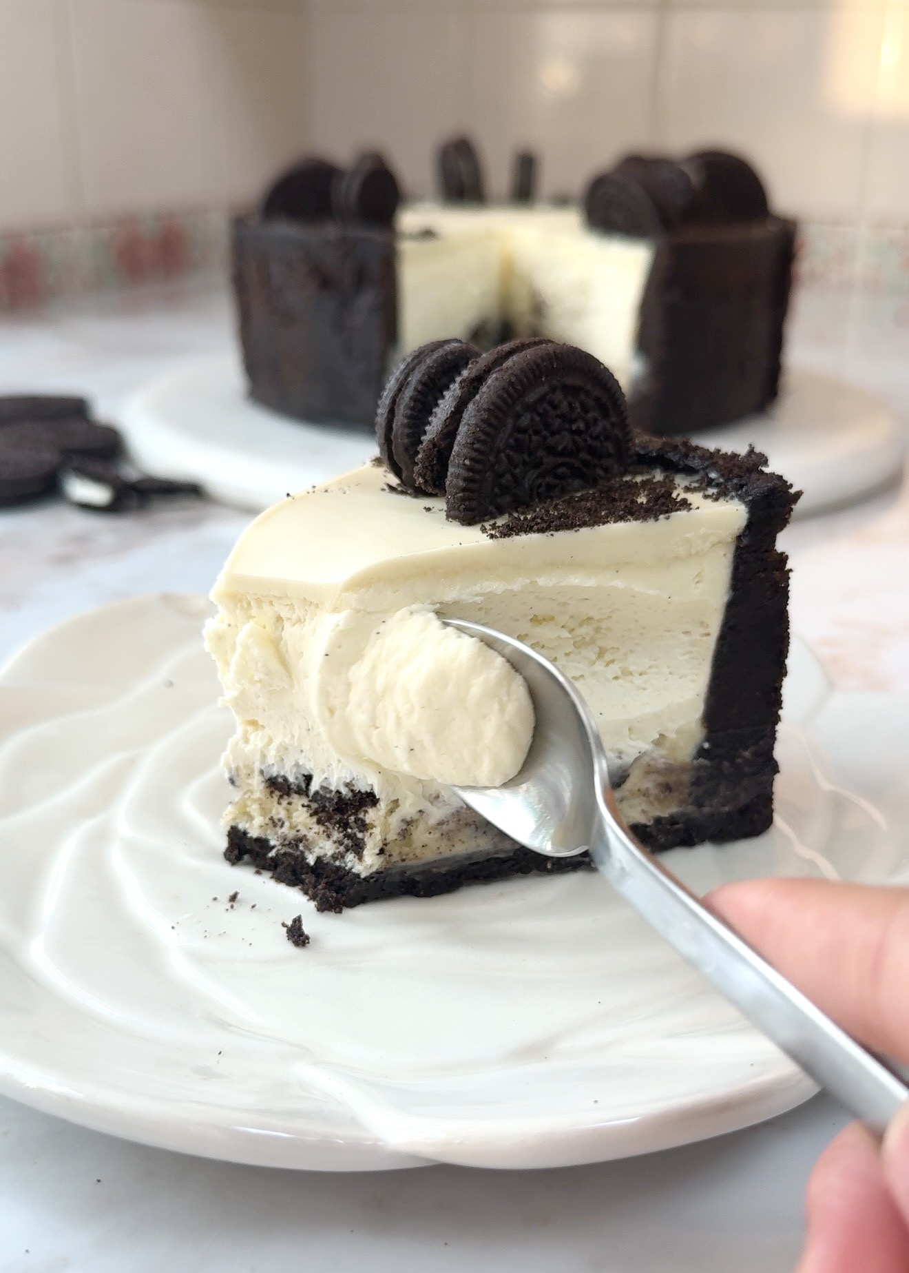 Creamy no bake Oreo cheesecake topped with melted white chocolate and crushed Oreo cookies