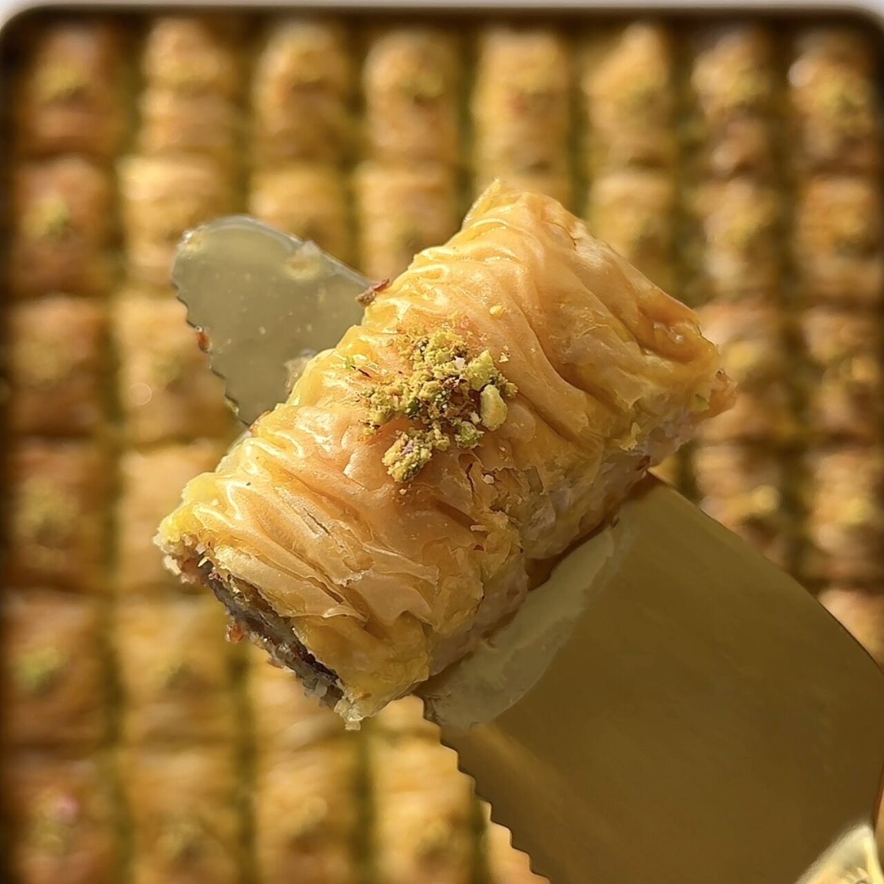 Golden crispy homemade baklava rolls drizzled with syrup and topped with crushed pistachios