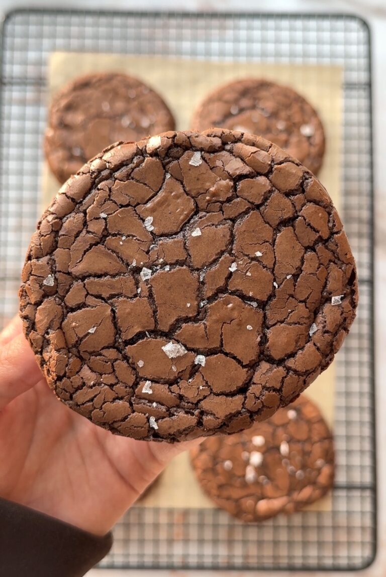 Shiny crackly brownie cookies with fudgy centres and flaky sea salt on a baking tray
