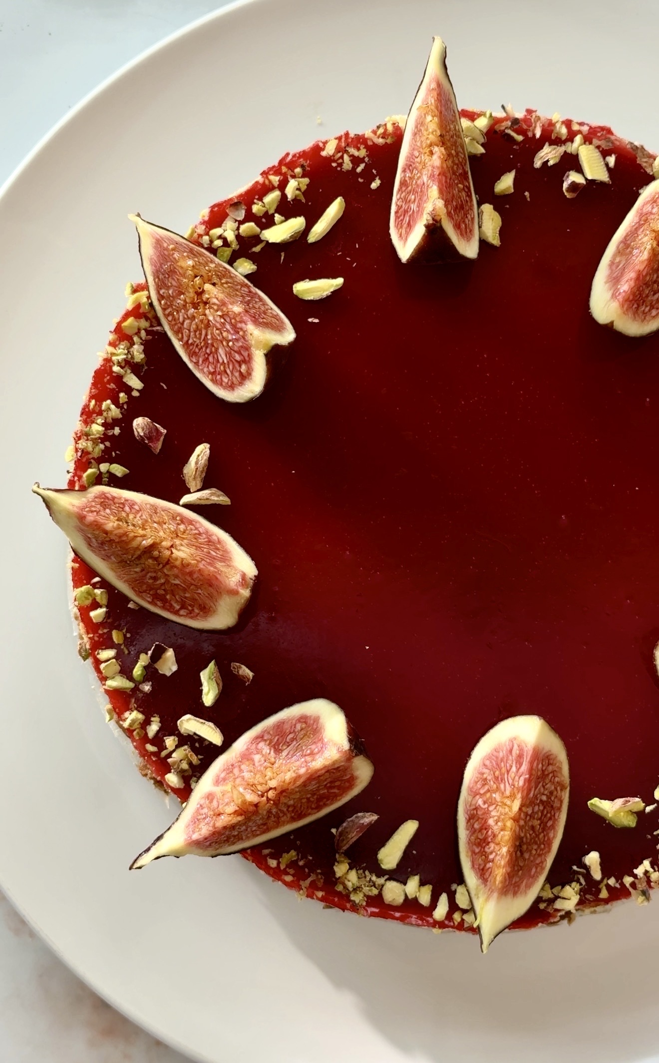 Baked fig and raspberry cheesecake with raspberry jelly topping, fresh figs and crushed pistachios on a Biscoff crust