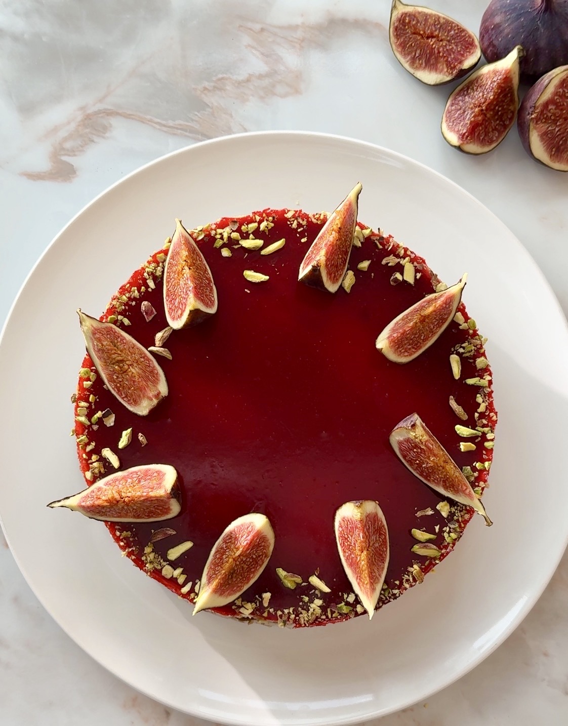 Baked fig and raspberry cheesecake with raspberry jelly topping, fresh figs and crushed pistachios on a Biscoff crust