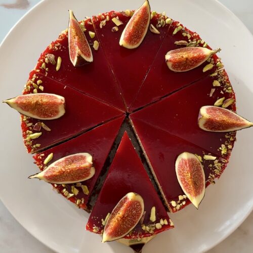 Baked fig and raspberry cheesecake with raspberry jelly topping, fresh figs and crushed pistachios on a Biscoff crust
