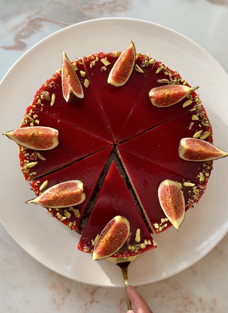 Baked fig and raspberry cheesecake with raspberry jelly topping, fresh figs and crushed pistachios on a Biscoff crust